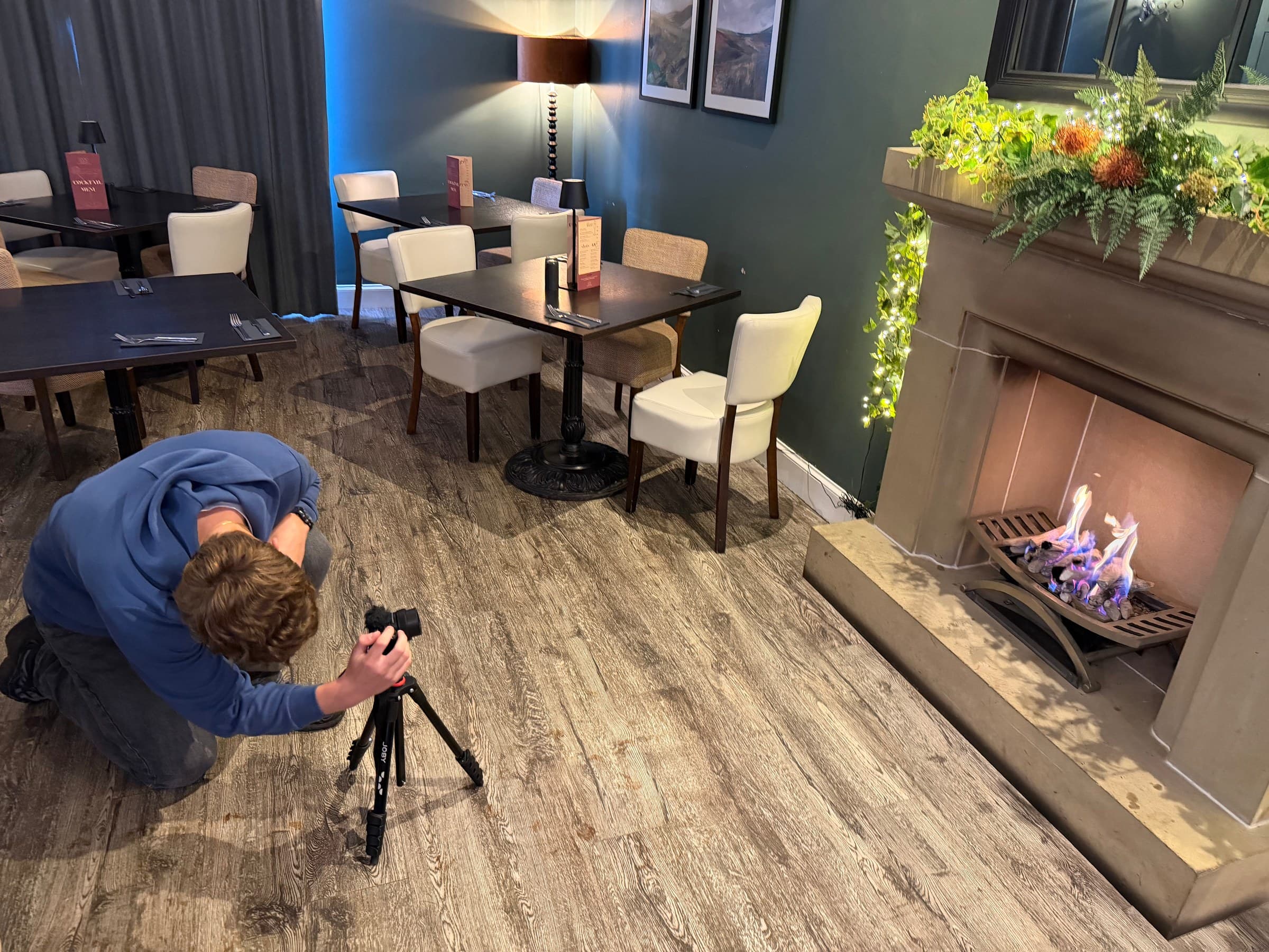 Sean kneeling on a restaurant floor to shoot low, camera on a small tripod
