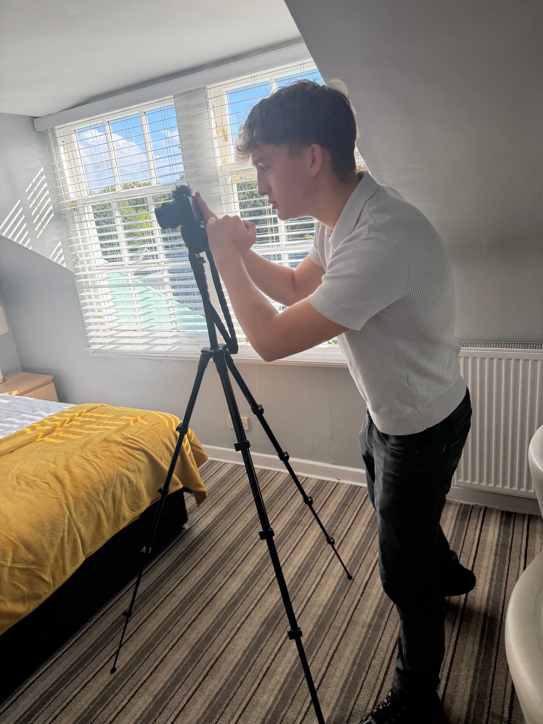 Sean photographing a guest bedroom by the window, camera on a tripod