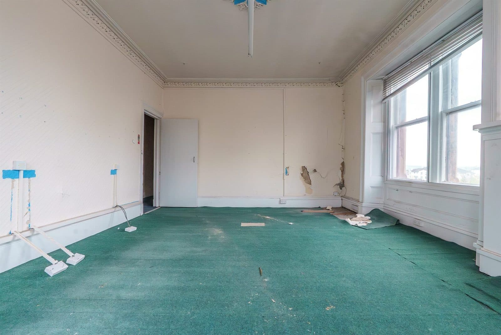 A tired period office with green carpet and cracked plaster before refurbishment