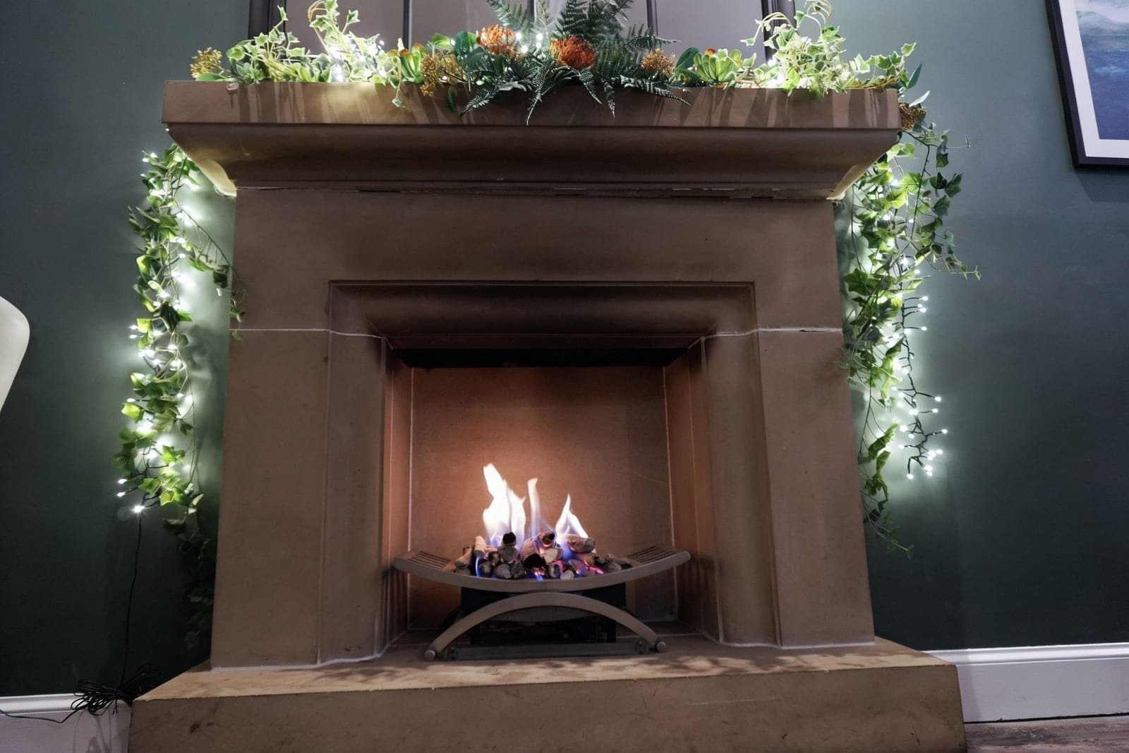 The finished photo: the stone fireplace lit, with fairy lights in the garland