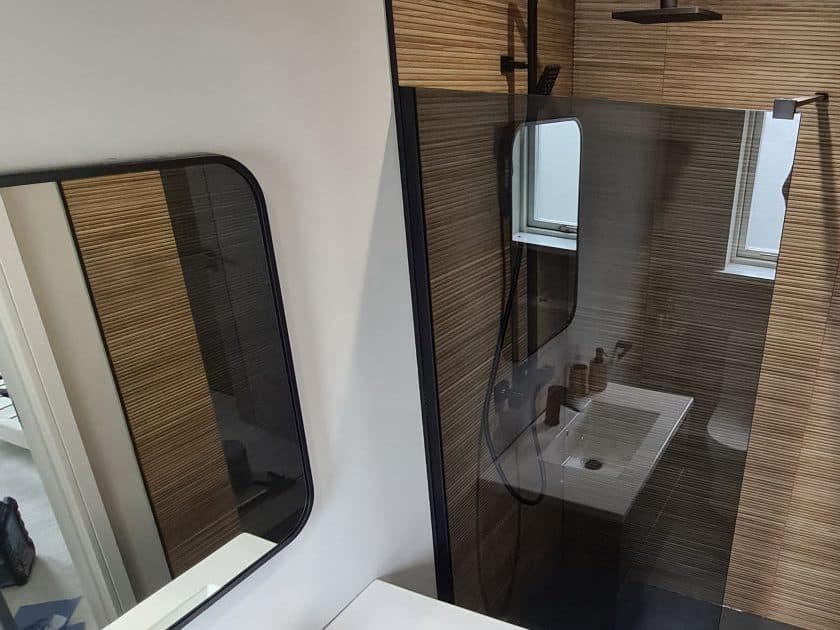 A shower room in ribbed timber-effect tiling with black fittings