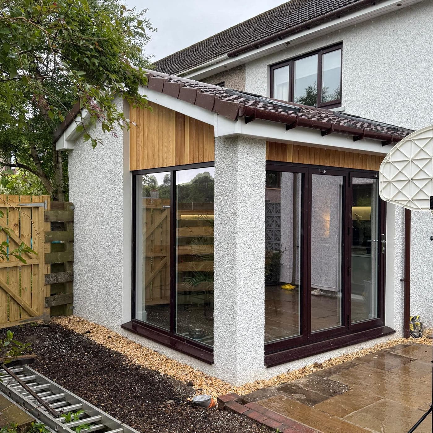 A garden room clad in cedar with dark timber-framed glazing